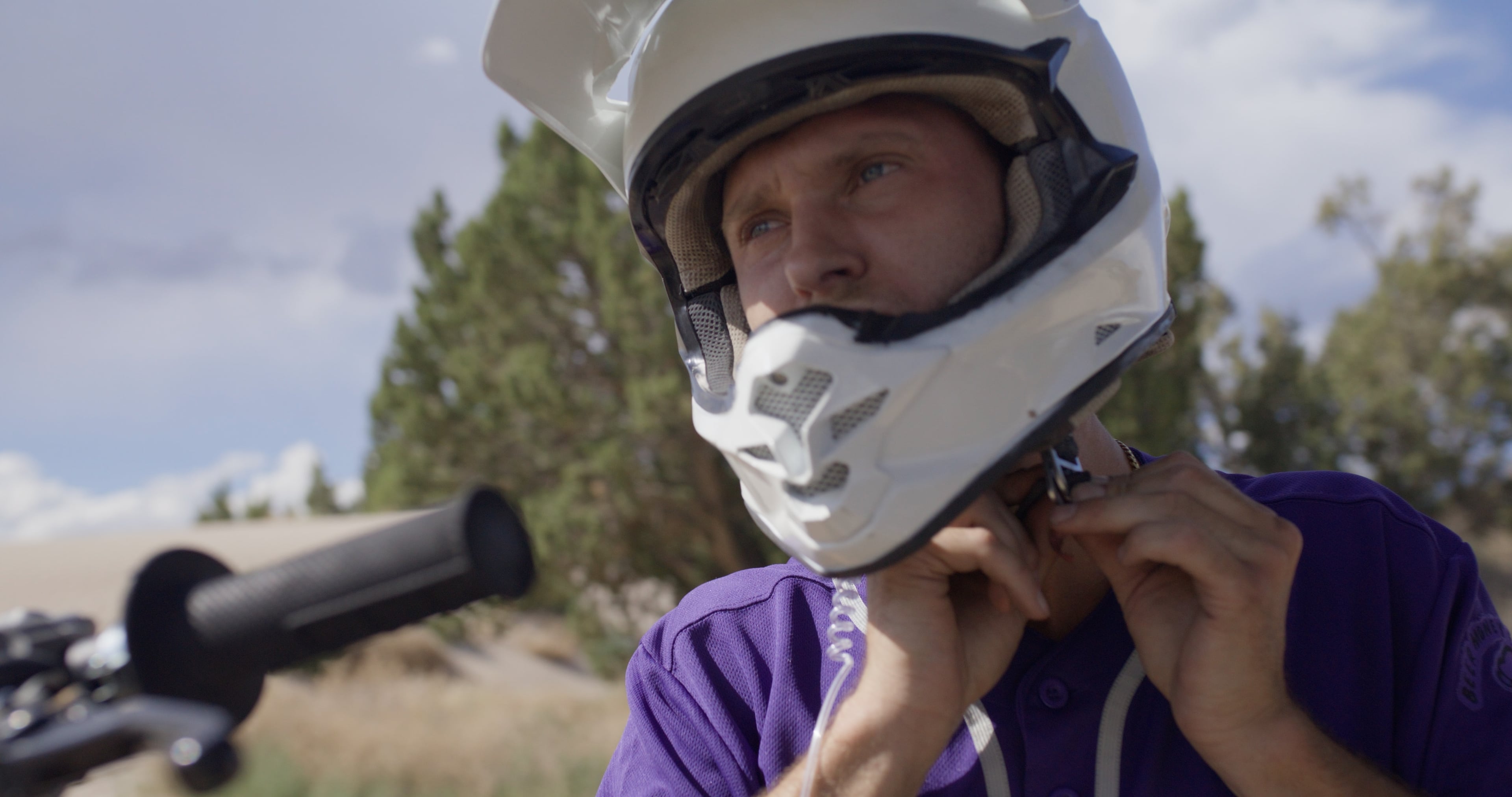 Motocross rider fastening a white helmet in harsh sun, plain Rec.709 conversion
